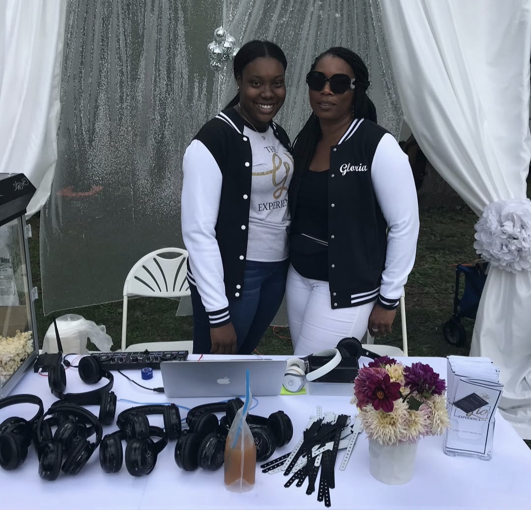 Gloria D. Cassell and her daughter behind The Glo Experience headphone setup.