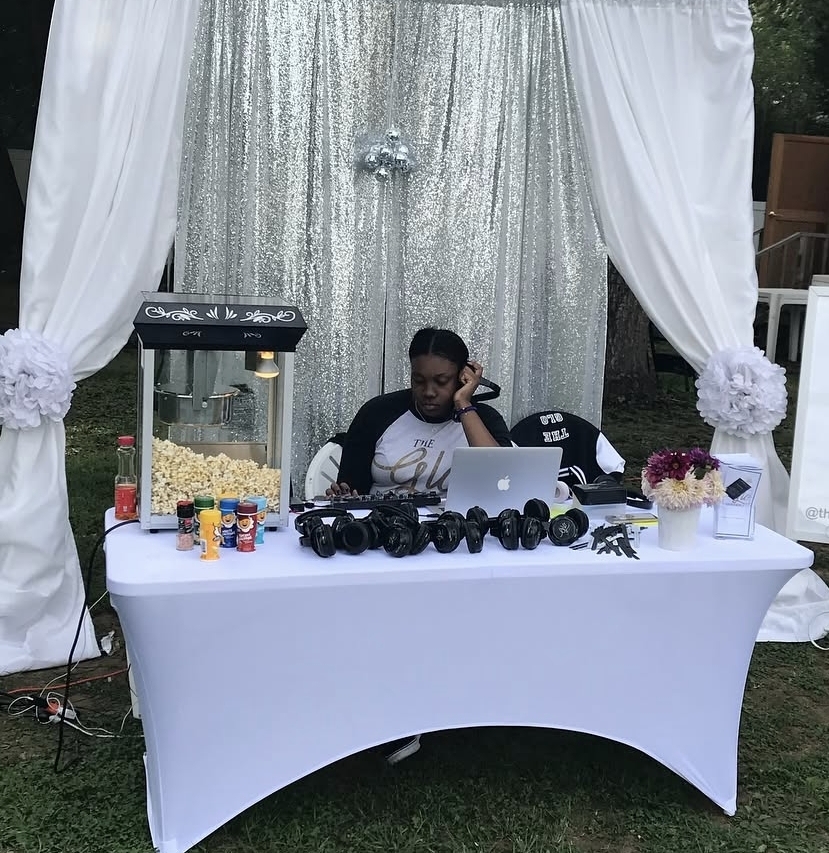 Gloria D. Cassell’s daughter wearing headphones beside music equipment at a vendor showcase event.